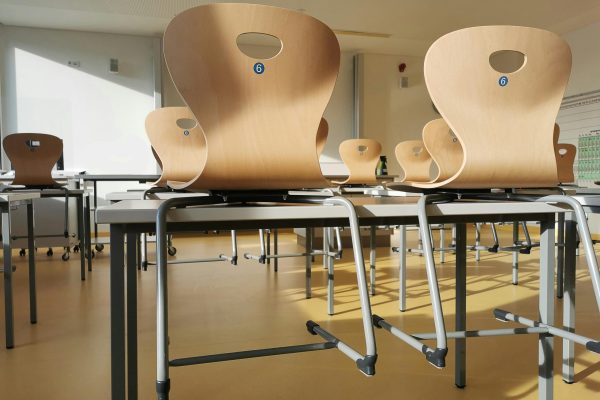 Bright and tidy empty classroom with wooden chairs and tables ready for students.